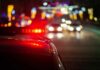 Police car with flashing red lights on a city street at night