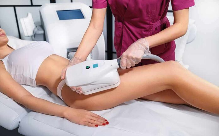 Therapist performing body contouring treatment on woman's thigh