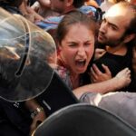 Protesters clash with riot police as woman shouts