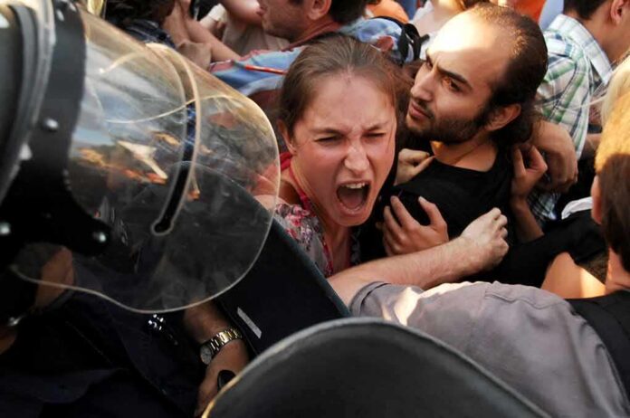 shutterstock_192867317 Protesters clash with riot police as woman shouts
