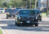Motorcade of black SUVs and sedans driving down a city street