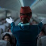 Flight attendant giving safety demonstration in airplane aisle