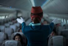 Flight attendant giving safety demonstration in airplane aisle