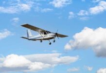 Single-engine light airplane flying against a blue sky with clouds