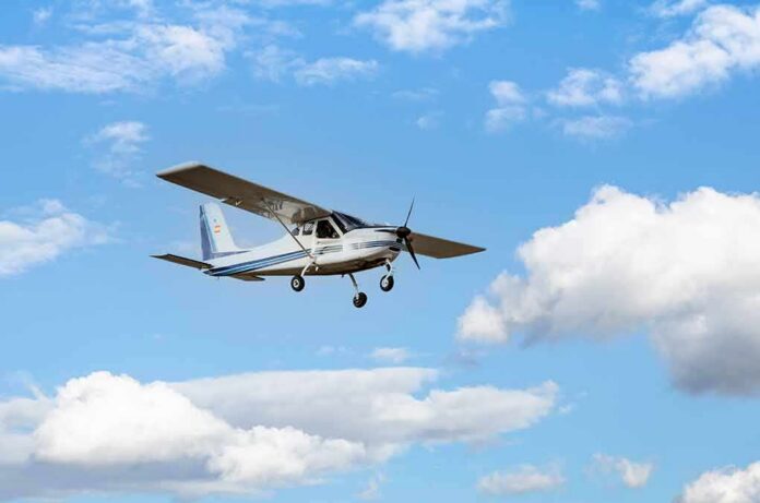 Single-engine light airplane flying against a blue sky with clouds