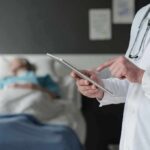 Surgery Error Leaves Woman Without Both Legs Doctor using tablet beside hospital patient