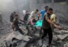 Rescuers carry an injured person on a stretcher through rubble