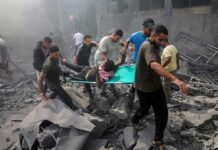 Rescuers carry an injured person on a stretcher through rubble