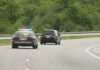 Police car with flashing lights following a minivan on a highway
