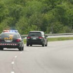 Police car with flashing lights following a minivan on a highway