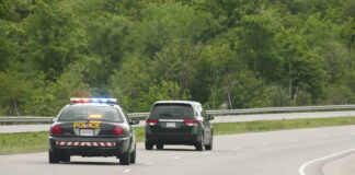 Police car with flashing lights following a minivan on a highway