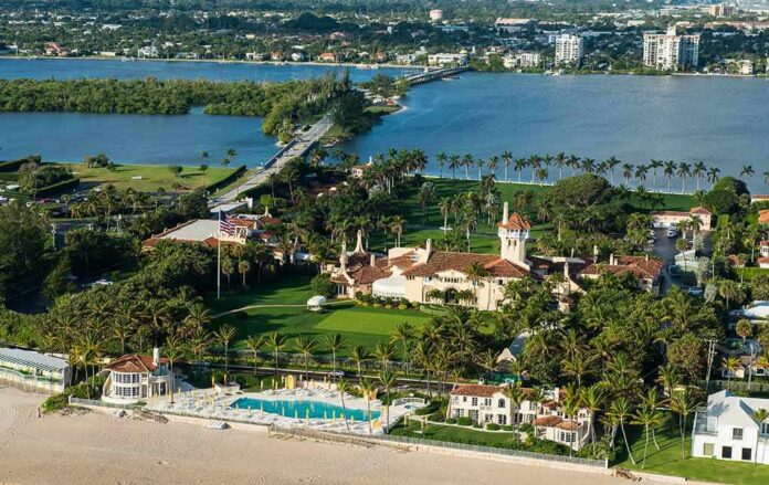 Aerial view of a waterfront estate with pool, lawns, and palm trees