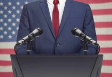 Speaker in suit at podium with microphones