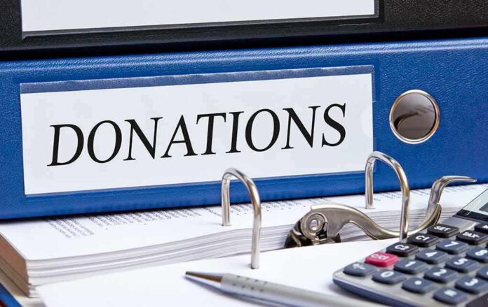 shutterstock_527198497 Blue binder labeled donations on a desk with papers and a calculator