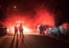 Firefighters and police at a nighttime car fire scene